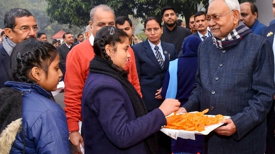 Bihar Chief Minister Nitish Kumar offers 'jalebi' to school students during the 75th Republic Day celebration at his official residence in Patna.(PTI)