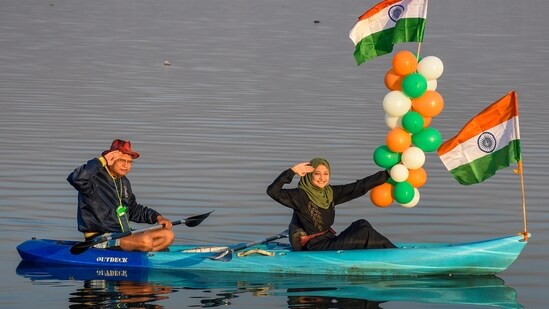 A Mumslim woman holding tricoloured balloons and national flag rides a boat on the River Tapi to celebrate 75th Republic Day in Surat.(PTI)