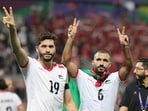 Palestine's forward Mahmoud Wadi and midfielder Oday Kharoub greet supporters
