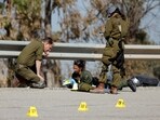 Israeli soldiers inspect a road for evidence and remains relating to the deadly October 7 attack by gunmen from Palestinian Islamist group Hamas, near Israel's border with Gaza in southern Israel 