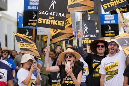Picketers carry signs on the picket line outside the office of Netflix in Los Angeles in September 2023. The Hollywood's writers strike was declared over when board members from their Union approved a contract agreement with studios, bringing the industry at least partly back from a historic halt in production. (Chris Pizzello/Invision/AP) Picketers carry signs on the picket line outside the office of Netflix in Los Angeles in September 2023. The Hollywood's writers strike was declared over when board members from their Union approved a contract agreement with studios, bringing the industry at least partly back from a historic halt in production. (Chris Pizzello/Invision/AP)