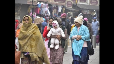People dressed in warm clothes on a cloudy day in Amritsar on Sunday. (Sameer Sehgal/HT)