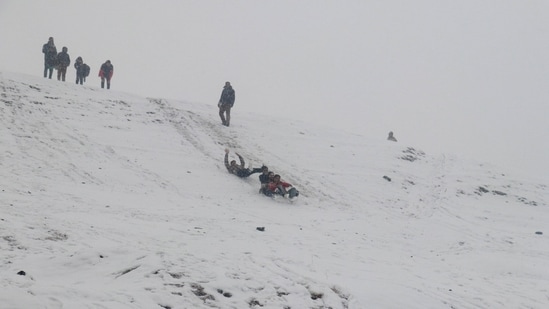 Kashmir is currently under the grip of "Chilla-i-Kalan," a 40-day harsh winter period during which a cold wave sweeps the region, causing a considerable drop in temperatures and leading to the freezing of water bodies and pipes. In the picture, tourists are seen sleighing down the slope in the snowy Gulmarg region on Sunday.(HT Photo)