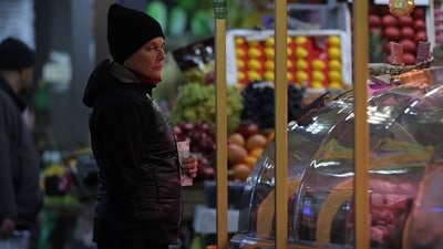 A customer holds a Russian rouble banknote while looking at foodstuffs at a market in Saint Petersburg, Russia. (Reuters)