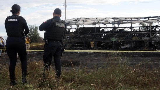 Agents of the Federal Police stand guard next to a burnt passenger bus after it crashed with a truck at the Mazatlan-Culiacan highway in the community of La Cruz, Sinaloa state, Mexico. (AFP)