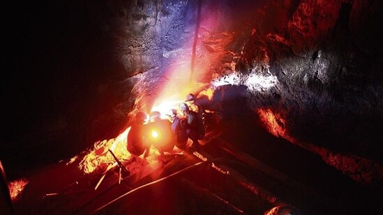 In a photograph dated January 29, 2013, miners keep warm by a fire inside a deep mine shaft near Rymbai village in Meghalaya. (AFP)