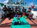 Commandos stand guard with a group of detained pirates after the Indian Navy freed a hijacked fishing vessel. (AP)