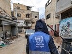 A man collects trash while wearing a jacket bearing the logo of the United Nations Relief and Works Agency for Palestine Refugees in the Near East (UNRWA) A man collects trash while wearing a jacket bearing the logo of the United Nations Relief and Works Agency for Palestine Refugees in the Near East (UNRWA)