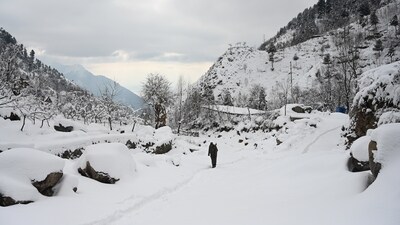A boy walks on a snow-covered hilly road after fresh snowfall in the outskirts of Srinagar on Friday (Waseem Andrabi /HT PHOTO)