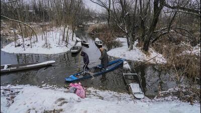 Boatmen removing melted snow water from a boat on the outskirts of Srinagar on Thursday. More snowfall is forecast over the weekend. (AP Photo)