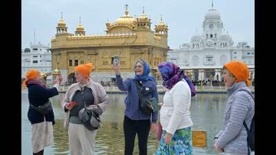 Tourists take pictures during their visit at the Golden Temple in Amritsar on Saturday. (AFP)