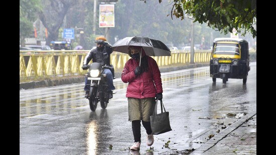 Commuters making their way through rain in Amritsar on Sunday. (Sameer Sehgal /HT)