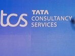 A man walks past a logo of Tata Consultancy Services (TCS) before a press conference.