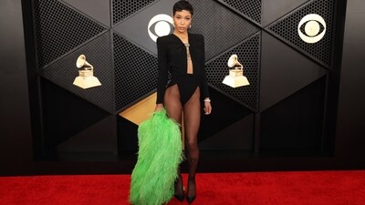 Coi Leray attended the Grammy Awards in a black bodysuit, putting a trendy and risque spin to the pantless trend. Her ensemble features a plunging neckline, full sleeves, and high-leg cut-outs. She styled the ensemble with sheer tights, black stilettos, a bright green feathery overcoat, and Jacob &amp; Co. watch and earrings.&nbsp; (REUTERS)
