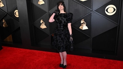 Lana Del Rey wore a black semi-sheer dress that hit just below the knees and featured huge shoulder pads and a subtle floral pattern to the Grammy Awards. She styled the ensemble with kitten heels, sheer gloves, a sleek black clutch, nude lips, winged eyeliner, dewy skin, and half-up, half-down hairstyle adorned with a black bow.&nbsp; (AFP)