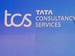 TCS Share price today: A man walks past a logo of Tata Consultancy Services (TCS) before a press conference.