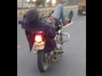The image, taken from the viral video, shows the man using the phone while steering the bike with his legs. 
