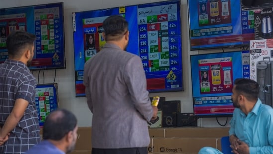 People monitor live election results on a screen in an electronic shop at a local market in Karachi, Pakistan, on Friday, Feb. 9, 2024. Vote-counting delays following Pakistan�s election on Thursday pointed to a disputed result as supporters of jailed former leader Imran Khan claimed a shock victory in a nation where the military retains a heavy influence on politics. Photographer: Asim Hafeez/Bloomberg (Bloomberg)