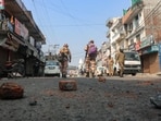 Security personnel walk past bricks and stones scattered on a road, a day after the religious clashes sparked following the destruction of a madrassa (an Islamic school) in Haldwani district of the northern state of Uttarakhand on February 9, 2024. 