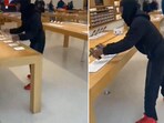 The image shows a man stealing iPhones from an Apple store. The image shows a man stealing iPhones from an Apple store.