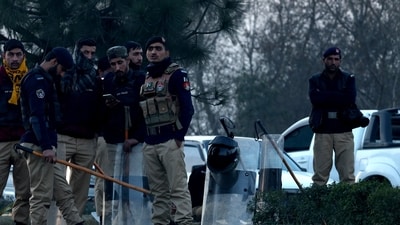 Pakistan Elections 2024: Police officers stand on a road divider as supporters of former Prime Minister Imran Khan's party, the Pakistan Tehreek-e-Insaf (PTI), block the Peshawar-Islamabad motorway. (Reuters)