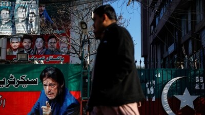 People walk past a banner with a picture of the former Prime Minister Imran Khan outside the party office of Pakistan Tehreek-e-Insaf (PTI). (REUTERS)