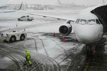 A man walks near a waitig plane as snow falls at John F. Kennedy International Airport Tuesday, Feb. 13, 2024, in New York. (AP Photo/Frank Franklin II) A man walks near a waitig plane as snow falls at John F. Kennedy International Airport Tuesday, Feb. 13, 2024, in New York. (AP Photo/Frank Franklin II)