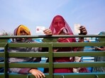 Women display their voter's identity card sitting in the back of a truck in Chachiyawas, near Ajmer, India, Saturday, Nov. 25, 2023. 