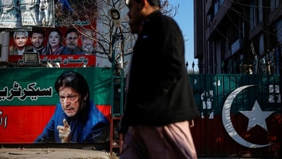 People walk past a banner with a picture of the former Prime Minister Imran Khan outside the party office of Pakistan Tehreek-e-Insaf (PTI). (REUTERS / File)