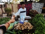 A customer pays cash to buy vegetables next to a QR code of Paytm, a digital payments firm, on display at a roadside market in Ahmedabad, India, February 5, 2024.REUTERS/Amit Dave