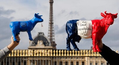 French dairy farmers hold cow sculptures bearing national colours and reading "fair milk", with the Eiffel Tower in the background, during a protest of French dairy farmers against the agriculture policy, near the Ecole Militaire in Paris. ( Credit: AFP)