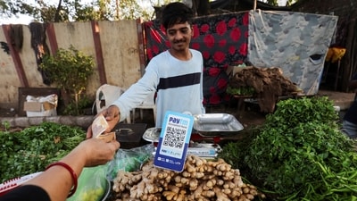 A customer pays cash to buy vegetables next to a QR code of Paytm, a digital payments firm, on display at a roadside market in Ahmedabad, India, February 5, 2024.REUTERS/Amit Dave (REUTERS)