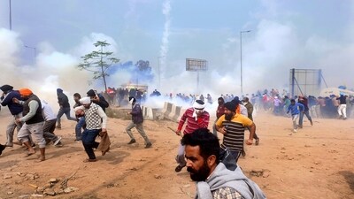 Farmers run for cover after police fired tear gas to disperse protesting farmers who were marching to New Delhi near the Punjab-Haryana border at Shambhu. (AP) Farmers run for cover after police fired tear gas to disperse protesting farmers who were marching to New Delhi near the Punjab-Haryana border at Shambhu. (AP)