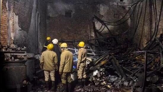 Fire brigade personnel look on after dousing a late fire at a paint factory in the Alipur area in northern New Delhi on February 16. (AP)