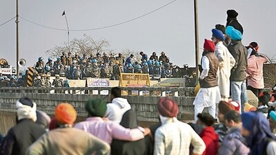 Protesting farmers stand facing the police barricade near Shambhu border on Friday. (AP) Protesting farmers stand facing the police barricade near Shambhu border on Friday. (AP)