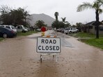 A road closure sign on a flooded road during a storm in Fontana, California, US.