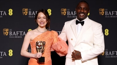 Emma Stone poses in the winners room with her award for Leading Actress for "Poor Things" next to Idris Elba. (REUTERS)