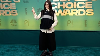 Billie Eilish embraced grandma-core on the red carpet at the People's Choice Awards 2024. The Bad Guy singer wore an off-white oversized button-down shirt, a black half-sleeve knit cardigan, and black baggy pants to the awards night. She styled the ensemble with black chunky sneakers, a black tie, colourful socks, metal rings, dainty earrings, and rimless glasses. Centre-parted open locks, blushed cheekbones, bushy brows, and glossy caramel lip shade rounded it off. (AFP) Billie Eilish embraced grandma-core on the red carpet at the People's Choice Awards 2024. The Bad Guy singer wore an off-white oversized button-down shirt, a black half-sleeve knit cardigan, and black baggy pants to the awards night. She styled the ensemble with black chunky sneakers, a black tie, colourful socks, metal rings, dainty earrings, and rimless glasses. Centre-parted open locks, blushed cheekbones, bushy brows, and glossy caramel lip shade rounded it off. (AFP)