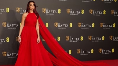 Dua Lipa arrived on the BAFTA Awards red carpet dressed in a statement-making red Valentino gown. The Levitating singer's show-stopping floor-length red gown featured a matching red cape, a halter silhouette, a pleated design, and a semi-cinched waist. The singer finished the look with minimal makeup that perfectly complemented her red hair. (AFP) Dua Lipa arrived on the BAFTA Awards red carpet dressed in a statement-making red Valentino gown. The Levitating singer's show-stopping floor-length red gown featured a matching red cape, a halter silhouette, a pleated design, and a semi-cinched waist. The singer finished the look with minimal makeup that perfectly complemented her red hair. (AFP)