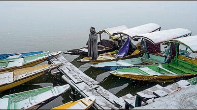 A man stands amid snow-covered boats on the Dal lake in Srinagar on Tuesday (AFP) A man stands amid snow-covered boats on the Dal lake in Srinagar on Tuesday (AFP)