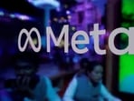 People are seen behind a logo of Meta Platforms, during a conference.