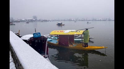 A boatman clears snow from a shikara anchored on the shores of the Dal Lake after fresh snowfall in Srinagar on Tuesday. (AP) A boatman clears snow from a shikara anchored on the shores of the Dal Lake after fresh snowfall in Srinagar on Tuesday. (AP)