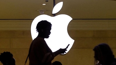 A women uses an iPhone mobile device as she passes a lighted Apple logo at the Apple store (Reuters)