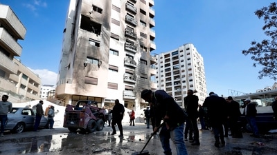 A man sweeps rubble near a residential building after a reported Israeli attack on Syria, according to The Syrian state TV. (AP)