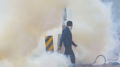 A man walks through tear gas at the site of the protest, as farmers march towards New Delhi to press for better crop prices promised to them in 2021, at Shambhu barrier, a border crossing between Punjab and Haryana. (Reuters)