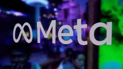 People are seen behind a logo of Meta Platforms, during a conference. (Reuters)
