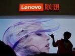 An employee gestures next to a Lenovo logo at Lenovo Tech World in Beijing, China.