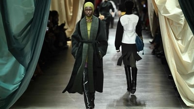 The Fendi collection presented classic and elegant looks with natural tones and monochromatic outfits. A model walked down the runway in a neon green mini dress paired with an oversized long jacket in dark green for the perfect contrast. The necklace and knee-length shiny black boots added the ultimate finishing touch. (AFP) The Fendi collection presented classic and elegant looks with natural tones and monochromatic outfits. A model walked down the runway in a neon green mini dress paired with an oversized long jacket in dark green for the perfect contrast. The necklace and knee-length shiny black boots added the ultimate finishing touch. (AFP)