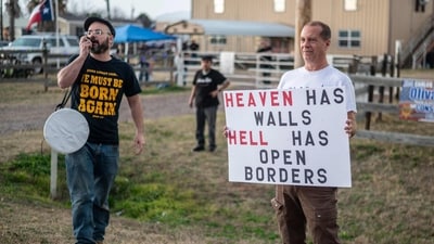 Protesters hold up signs and speak through a bullhorn supporting the "Take Our Border Back" convoy near Cornerstone Childrens Ranch near Quemado, Texas (AFP) Protesters hold up signs and speak through a bullhorn supporting the "Take Our Border Back" convoy near Cornerstone Childrens Ranch near Quemado, Texas (AFP)
