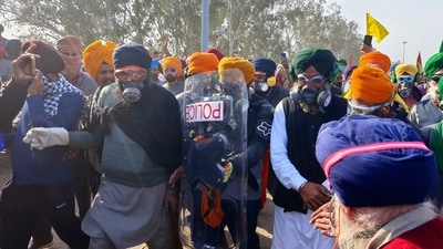 Farmer leader Sarwan Singh Pandher, in green turban wearing a gas mask, walks with protesting farmers towards the police barricade near Shambhu border. (AP) Farmer leader Sarwan Singh Pandher, in green turban wearing a gas mask, walks with protesting farmers towards the police barricade near Shambhu border. (AP)